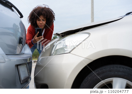 Half Thai African driver check for damage after a car accident before taking pictures and sending insurance. Online car accident insurance claim after submitting photos and evidence to an insurance. 110204777