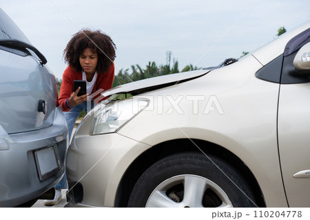 Half Thai African driver check for damage after a car accident before taking pictures and sending insurance. Online car accident insurance claim after submitting photos and evidence to an insurance. 110204778