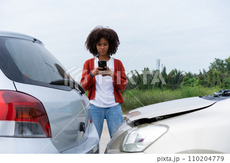 Half Thai African driver check for damage after a car accident before taking pictures and sending insurance. Online car accident insurance claim after submitting photos and evidence to an insurance. 110204779