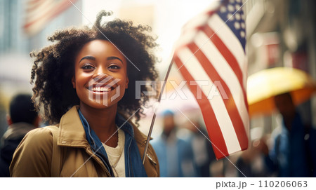 Happy, smiling afro black woman with American flag in the city on the Independence Day holidays of the United States of America. Happy, smiling afro black woman with American flag in the city on the Independence Day holidays of the United States of America. 110206063