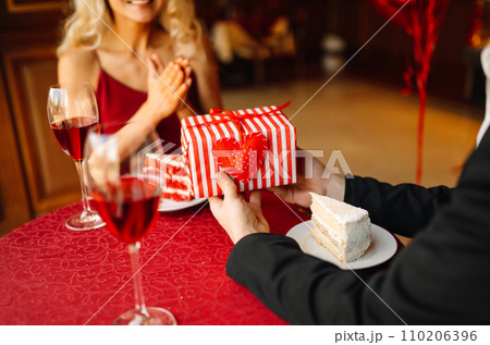 Couple in love exchanges gifts for Valentine's Day in a cafe at the table. Concept of holiday, love. Couple in love exchanges gifts for Valentine's Day in a cafe at the table. Concept of holiday, love. 110206396