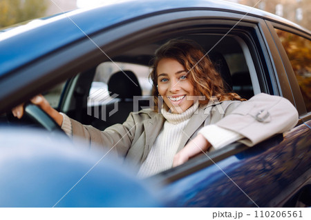 Pretty woman driver smiling to you from car. Automobile Journey, lifestyle concept. Car sharing. 110206561