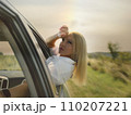 A beautiful girl rides in a car at speed and enjoys the wind from the window, rest from work and bustle, serenity and freedom. High quality photo 110207221