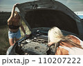 an accident on the road, a car broke down, two beautiful girl models are repairing the motor. Car problem. Friends waiting for service. In the countryside . High quality photo 110207222