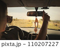 A beautiful girl rides in a car at speed and looks in the rear-view mirror, rest from work and bustle, serenity and freedom. Escape from problems and a chance to be alone. High quality photo 110207227