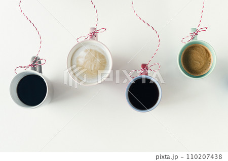 Winter garland with Christmas toy made from cups of coffee hanging on a red white string or twine tied in a bow. White table. Winter Concept. Creative 110207438