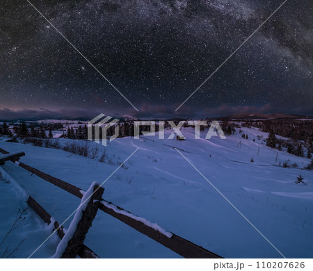 Night countryside hills, groves and farmlands in winter remote alpine mountain village, and starry sky with Milkyway above. Ukraine, Voronenko. 110207626