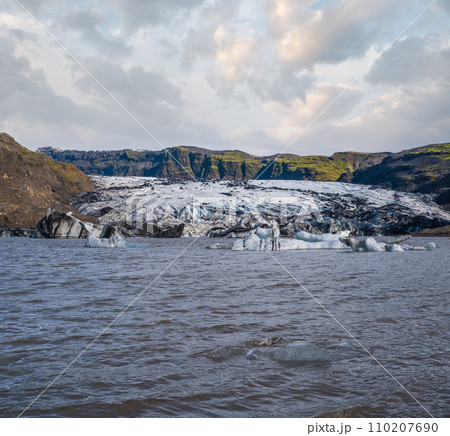 Solheimajokull glacier in southern Iceland. The tongue of this glacier slides from the volcano Katla. Beautiful glacial lake lagoon with ice blocks and surrounding mountains. People unrecognizable. 110207690