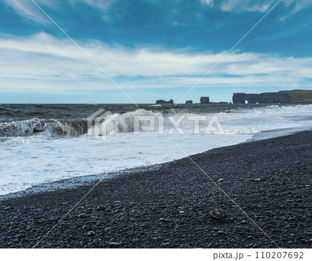 Picturesque autumn Dyrholaey Cape and  rock formations view from Reynisfjara ocean black volcanic sand beach. Vik, South Iceland. 110207692