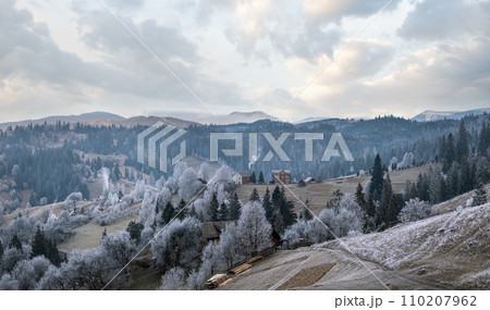 Winter coming. Picturesque foggy and moody morning scene in late autumn mountain countryside with hoarfrost on grasses, trees, slopes. Ukraine, Carpathian Mountains. Winter coming. Picturesque foggy and moody morning scene in late autumn mountain countryside with hoarfrost on grasses, trees, slopes. Ukraine, Carpathian Mountains. 110207962