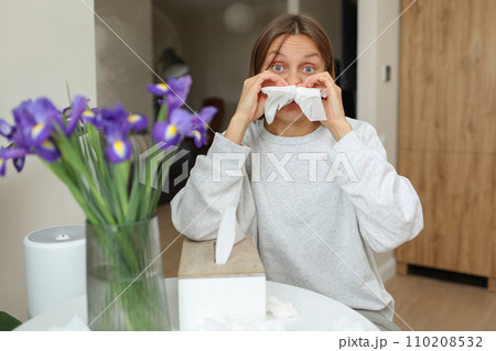 Allergy, flu, cold, rhinitis. Funny face of sick woman with paper tissues inside nose from runny nose and sneezes at home. Hay fever, sinusitis and female with viral infection blowing in handkerchief Allergy, flu, cold, rhinitis. Funny face of sick woman with paper tissues inside nose from runny nose and sneezes at home. Hay fever, sinusitis and female with viral infection blowing in handkerchief 110208532