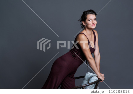 Fashionable young woman posing on dark gray studio background Fashionable young woman posing on dark gray studio background 110208818