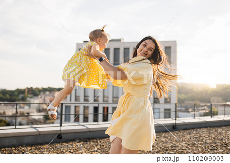 Adult lady holding and spinning with kid on city roof 110209003