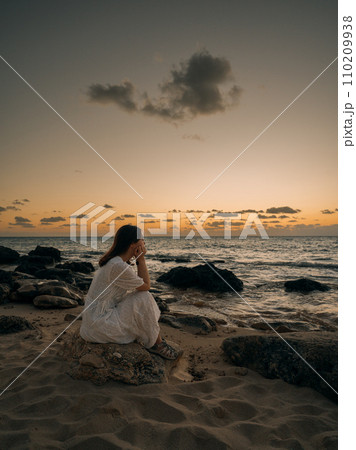 夕日の海岸に座る女性 夕日の海岸に座る女性 110209938
