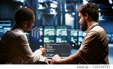 IT developers team writing server script code in data center on laptop terminal. Teamworking programmers doing maintenance work in high tech facility updating rigs software 110210743