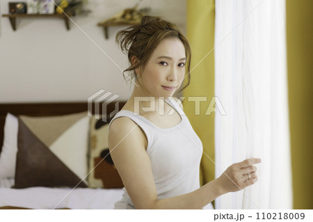 朝カーテンを開ける若い女性のポートレート 朝カーテンを開ける若い女性のポートレート 110218009