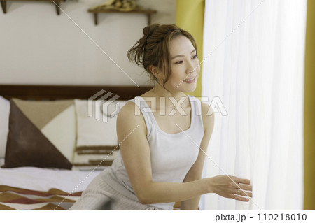 朝カーテンを開ける若い女性のポートレート 朝カーテンを開ける若い女性のポートレート 110218010