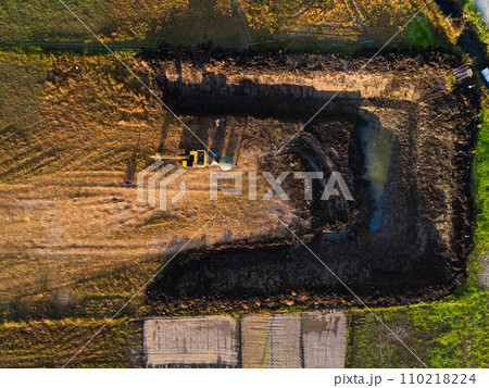 Excavating dirt into a dump truck to build a water storage pond for use in the dry season for agriculture. Aerial view of a backhoe is working. 110218224