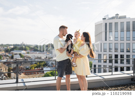 Pleased family and dog standing together on roof of building 110219098