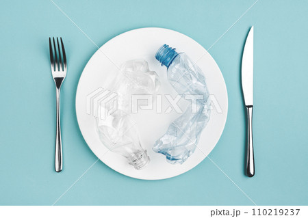 Bottle on the plate and other plastic waste on blue background Bottle on the plate and other plastic waste on blue background 110219237