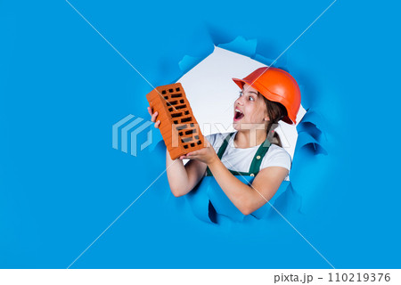 girl in helmet plays builder with brick. building a house. Kid build construction. engineer teen is construction worker. Professional craftsman or workman. International workers day. copy space 110219376