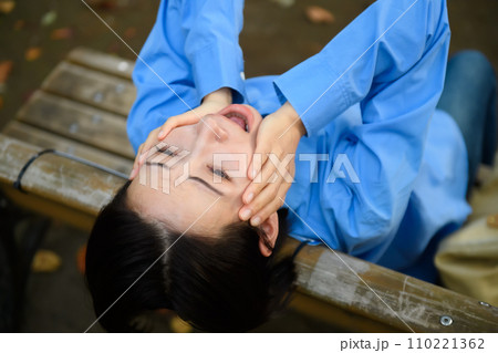 ベンチに座って悩む女性 ベンチに座って悩む女性 110221362