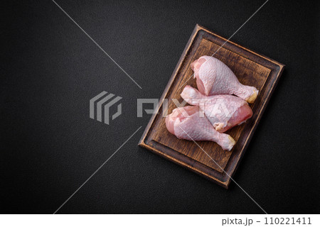 Raw chicken legs with salt, spices and herbs on a dark concrete background Raw chicken legs with salt, spices and herbs on a dark concrete background 110221411