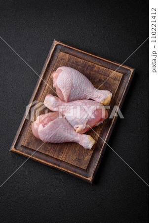 Raw chicken legs with salt, spices and herbs on a dark concrete background Raw chicken legs with salt, spices and herbs on a dark concrete background 110221412