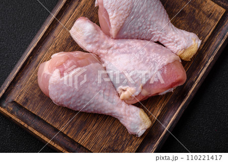 Raw chicken legs with salt, spices and herbs on a dark concrete background Raw chicken legs with salt, spices and herbs on a dark concrete background 110221417