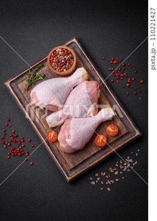 Raw chicken legs with salt, spices and herbs on a dark concrete background Raw chicken legs with salt, spices and herbs on a dark concrete background 110221427
