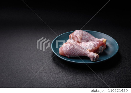 Raw chicken legs with salt, spices and herbs on a dark concrete background 110221429