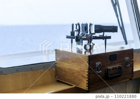 Nautical black sextant placed on wooden box in navigational bridge. Navigational equipment. Celestial navigation. Nautical black sextant placed on wooden box in navigational bridge. Navigational equipment. Celestial navigation. 110221880
