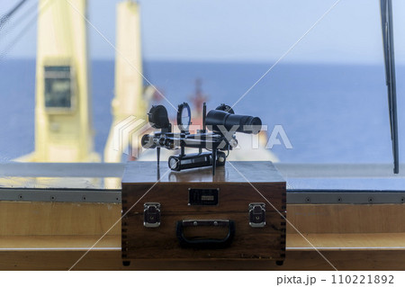 Nautical black sextant placed on wooden box in navigational bridge. Navigational equipment. Celestial navigation. Nautical black sextant placed on wooden box in navigational bridge. Navigational equipment. Celestial navigation. 110221892