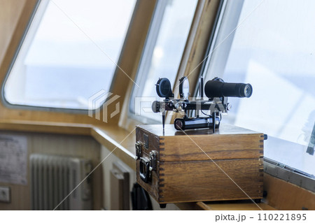 Nautical black sextant placed on wooden box in navigational bridge. Navigational equipment. Celestial navigation. Nautical black sextant placed on wooden box in navigational bridge. Navigational equipment. Celestial navigation. 110221895
