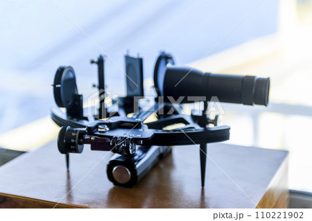 Nautical black sextant placed on wooden box in navigational bridge. Navigational equipment. Celestial navigation. 110221902