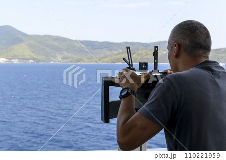 Navigational officer taking bearing with azimuth ring on gyro compass on the wing of navigational bridge. Navigational equipment usage. Observations. 110221959