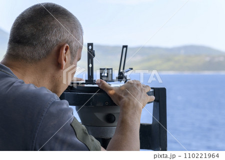 Navigational officer taking bearing with azimuth ring on gyro compass on the wing of navigational bridge. Navigational equipment usage. Observations. 110221964