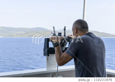Navigational officer taking bearing with azimuth ring on gyro compass on the wing of navigational bridge. Navigational equipment usage. Observations. 110221976