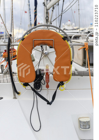 Man over board lifebouy with rope for yacht. White sailing yacht in marina, view from the stern. MOB. Safety at sea. SOLAS. Yachting concept. 110223710