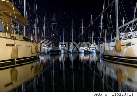 Sailing yachts in marina at night time. Mediterranean yacht port with sailing boats. Darkness. Calm weather. Yachting concept. Sailing yachts in marina at night time. Mediterranean yacht port with sailing boats. Darkness. Calm weather. Yachting concept. 110223711