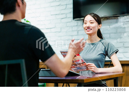 スポーツジムで入会案内を受ける女性 スポーツジムで入会案内を受ける女性 110223808
