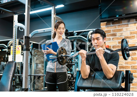 フィットネスジムでトレーナーの指導を受ける男性 110224028