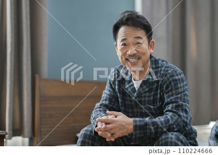 カメラ目線で笑顔のパジャマを着た50代半ばの男性 110224666