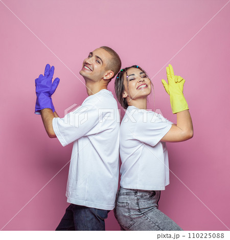 Happy young woman and man ready to clean house on colorful pink background 110225088