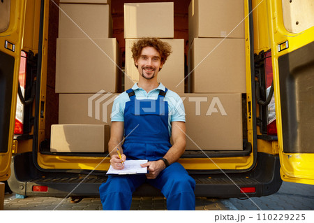 Professional young male courier providing parcel management before shipping 110229225