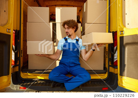 Delivery courier comparing parcel boxes 110229226