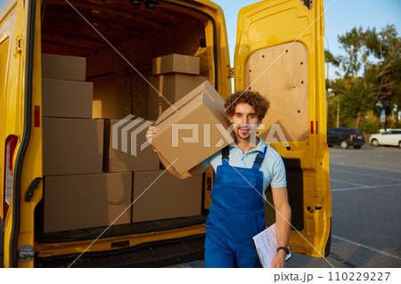 Deliveryman carrying cardboard boxes with purchased items in hand 110229227