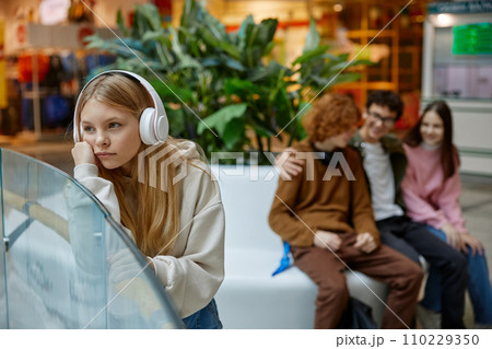 Little girl feeling upset to be ignoring with older friends, in shopping mall 110229350