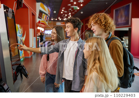 Teen friends using modern self-service kiosk at shopping mall Teen friends using modern self-service kiosk at shopping mall 110229403