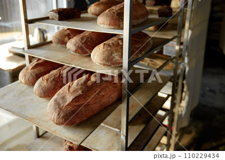 Steel rack with bread loaf on baking sheet in commercial kitchen 110229434